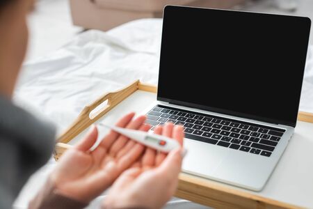 cropped view of ill woman with fever having online consultation with doctor on laptopの写真素材
