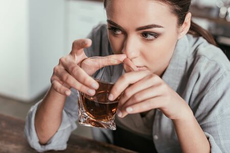 High angle view of woman holding whiskey glass and looking awayの写真素材