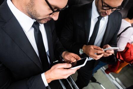 cropped view of businessman in suit using smartphone in elevatorの写真素材
