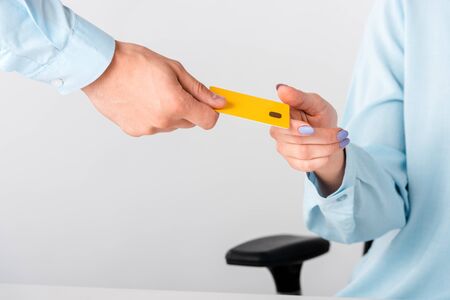 cropped view of man giving yellow credit card template to woman isolated on whiteの写真素材