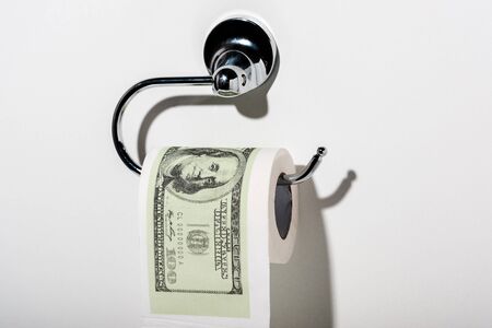toilet paper with dollar banknote near shadow on whiteの写真素材