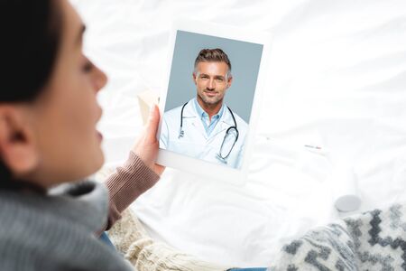 diseased woman having online consultation with male doctor on digital tabletの写真素材
