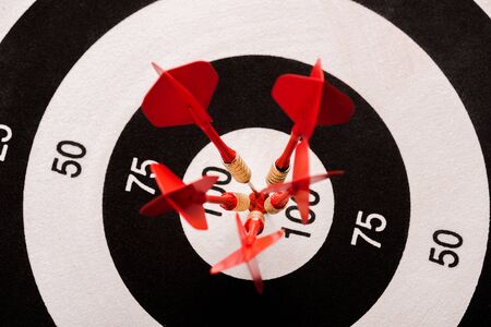 top view of black and white dartboard with red arrows