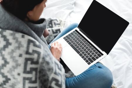 cold woman having online consultation with doctor on laptop with blank screenの写真素材