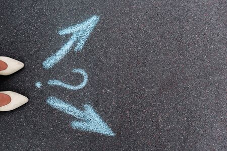 top view of woman standing near directional arrows and question mark on asphalt