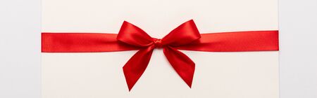 panoramic shot of red satin bow on envelope isolated on white