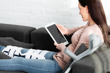 woman with broken leg having online consultation with doctor on digital tablet at homeの写真素材