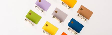 panoramic shot of credit card templates near cash rolls isolated on white