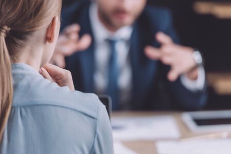 back view of young businesswoman near gesturing colleague