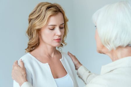 back view of mother hugging sad daughter isolated on grey