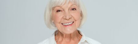 panoramic shot of attractive and smiling woman looking at camera isolated on grey
