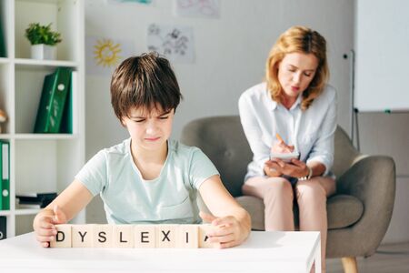 selective focus of kid with dyslexia holding cubes with lettering dyslexiaの写真素材