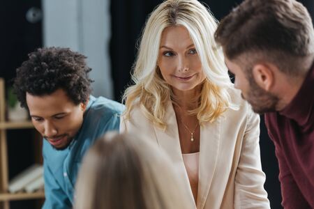 selective focus of attractive businesswoman looking at colleague at business meeting with...