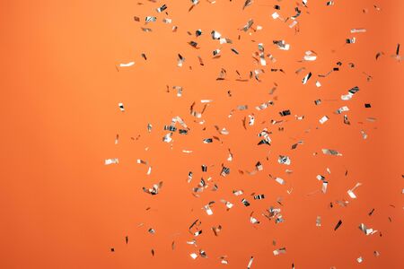 shiny silver confetti on orange backgroundの写真素材