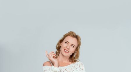 panoramic shot of attractive and dreamy woman looking up isolated on greyの写真素材