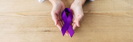panoramic shot of doctor holding purple ribbon in clinic