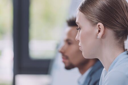 selective focus of young businesswoman near african american colleague