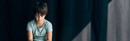 panoramic shot of sad kid with dyslexia on black background