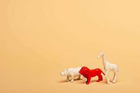 Toy lion, rhinoceros and giraffe on yellow background, animal welfare concept