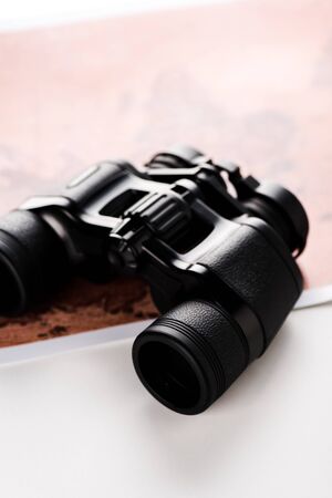 selective focus of binoculars near map on white 