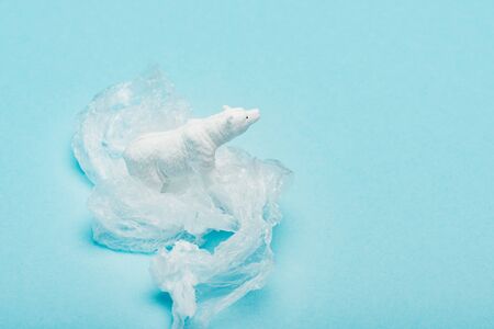 Polar bear on plastic bag on blue background, animal welfare concept