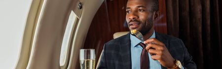 panoramic shot of africna american man eating in private jet