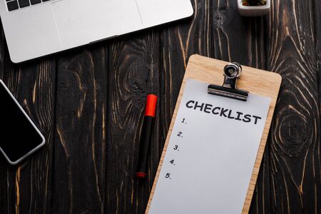 top view of gadgets near checklist and red marker pen on table, e-commerce concept