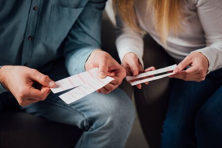 partial view of two gamblers checking lottery ticketsの写真素材