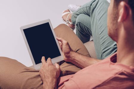cropped view of couple using digital tablet with blank screen together isolated on greyの写真素材