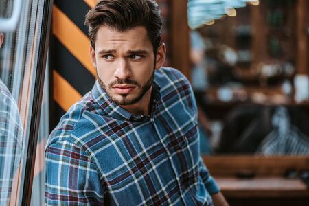 confused bearded man looking away in barbershopの写真素材