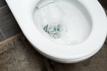 clean white toilet bowl with flushing money in modern restroom with grey tileの写真素材