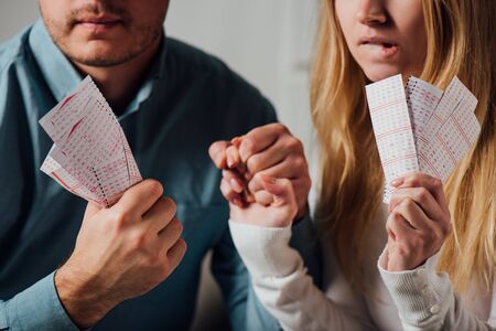 cropped view of two worried gamblers holding hands while waiting for lottery resultsの写真素材