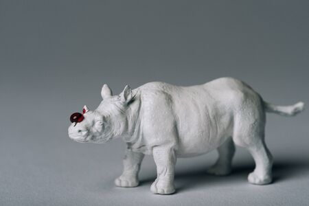 White toy rhinoceros with blood on grey background, hunting for horn conceptの写真素材