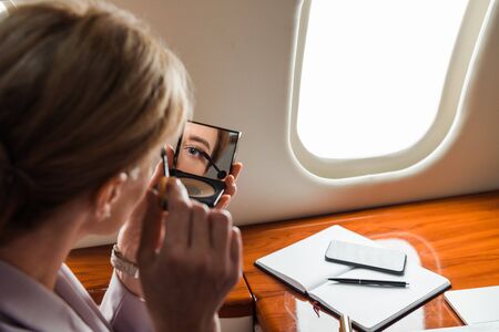 selective focus of businesswoman apply mascara in private planeの写真素材
