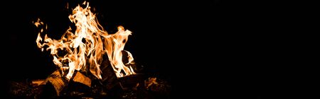 panoramic shot of logs burning in camp fire in darknessの写真素材