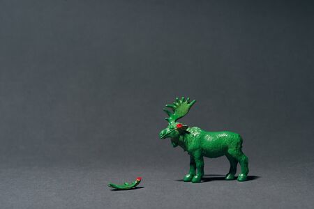 Green toy moose with horn on grey background, hunting for horns concept