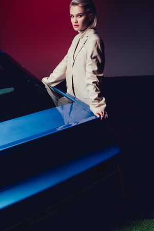 attractive and stylish woman in suit touching retro car