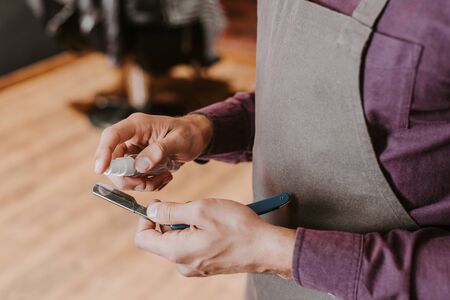 cropped view of barber holding antibacterial spray near razor の写真素材