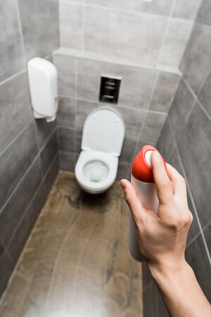 cropped view of man holding air freshener in modern restroom with grey tileの写真素材