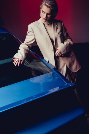 attractive and stylish woman in suit touching retro carの写真素材