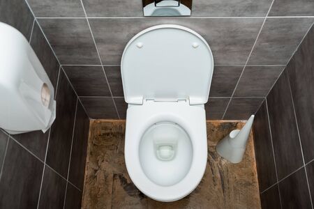 ceramic clean toilet bowl in modern restroom with grey tile and toilet brushの写真素材
