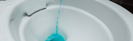 close up view of blue liquid detergent pouring into ceramic clean toilet bowl, panoramic shotの写真素材