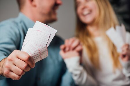 cropped view of happy man and woman holding hands while holding lottery ticketsの素材 [FY310135714651]