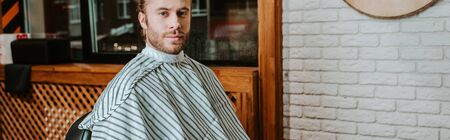 panoramic shot of handsome bearded man sitting in barbershopの写真素材