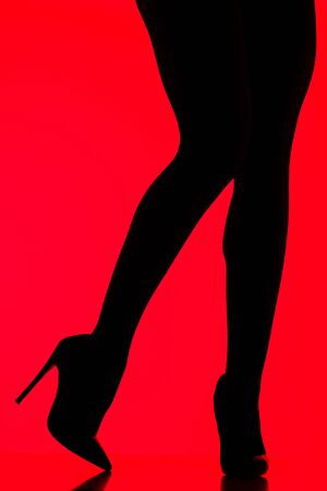 silhouette of sexy woman in heels posing on redの写真素材
