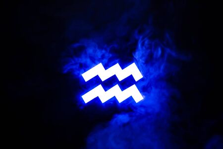 blue illuminated Aquarius zodiac sign with smoke on backgroundの写真素材