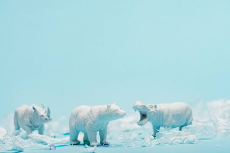 White toys of hippopotamus, rhinoceros and bear with plastic garbage on blue background, animal welfare conceptの写真素材