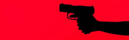 cropped view of silhouette of criminal woman holding gun isolated on red, panoramic shotの写真素材