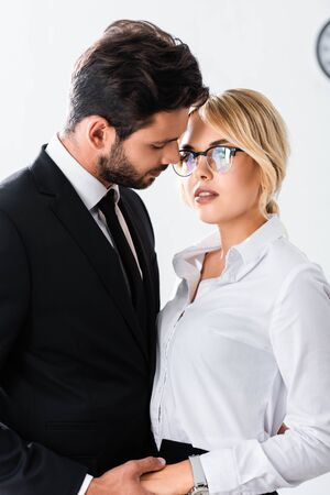 Business couple holding hands while flirting in officeの写真素材