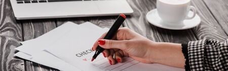 panoramic shot of woman holding marker pen near checklist on table, e-commerce concept